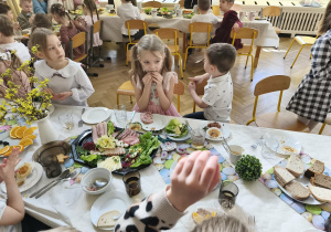 Na zdjęciu widzimy dzieci, które siedzą przy wielkanocnym stole i jedzą śniadanie.