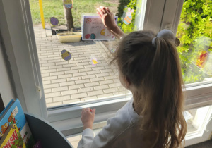 Na zdjęciu widzimy dziewczynkę, która zdejmuje list od Zajączka.