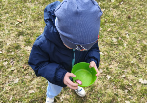Na zdjęciu widzimy chłopca, który trzyma w ręku miseczkę z jajkiem czekoladowym.