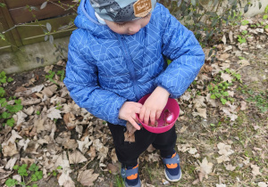 Na zdjęciu widzimy chłopca, który trzyma w ręku miseczkę z jajkiem czekoladowym.