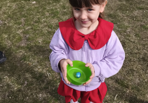 Na zdjęciu widzimy dziewczynkę, która w ręku trzyma miseczkę z jajkiem.