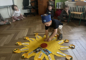 Chłopiec wkłada świeczkę w drewniany tort.