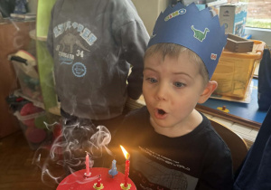 Chłopiec zdmuchuje świeczki na torcie.