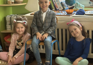 Chłopiec w koronie siedzi wśród innych dzieci.