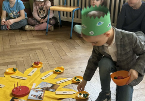 Chłopiec rozkłada koraliki na "słoneczku urodzinowym".