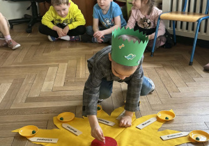 Chłopiec wkłada świeczkę w tort.