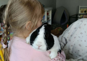 Na zdjęciu widzimy dziewczynkę, która trzyma królika i się do niego przytula.
