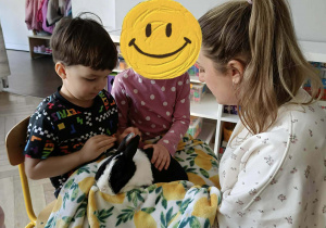 Na zdjęciu widzimy chłopca, który trzyma na kolanach królika. Dziewczynka obok niego głaszcze królika.