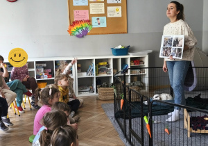 Na zdjęciu widzimy grupkę dzieci, które słuchają ciekawostek o królikach przekazywanych przez Panią.