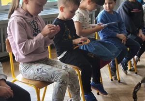 Na zdjęciu widzimy dzieci, które trzymają akcesoria do wyczesywania królików.