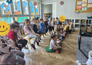 Na zdjęciu widzimy grupkę dzieci, które słuchają ciekawostek o królikach.