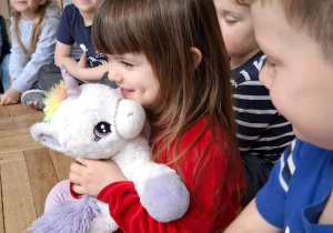 dziewczynka przytula maskotkę jednorożca