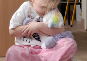 dziewczynka przytula maskotkę jednorożca