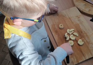 Chłopiec kroi sałatkę owocową.