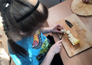 Chłopiec kroi sałatkę owocową.