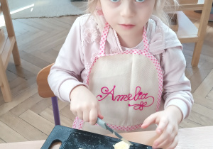 Dziewczynka kroi sałatkę owocową.