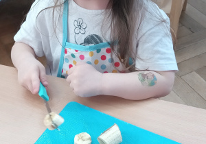 Dziewczynka kroi sałatkę owocową.