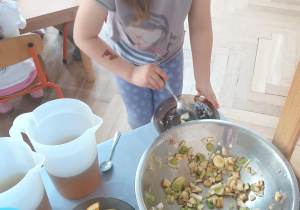 Dziewczynka nakłada sałatkę owocową.