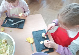 Dzieci kroją sałatkę owocową.