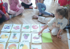 Dziewczynka zakrywa jeden owoc.