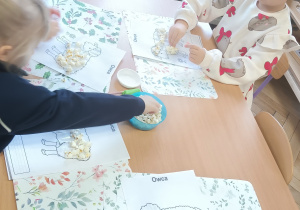 Dzieci ozdabiają owieczkę popcornem.