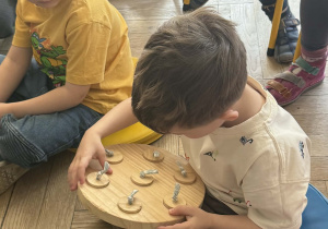 Chłopiec ogląda zabawkę drewnianą dla królików.