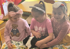 Zdjęcie przedstawia dziewczynki głaszczące królika.