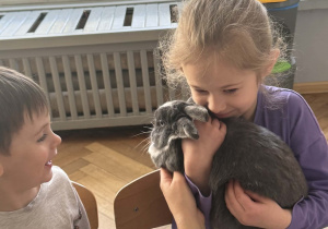 Na zdjęciu dziewczynka trzyma królika na ramieniu.