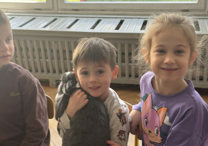 Na zdjęciu chłopiec trzyma królika na ramieniu.