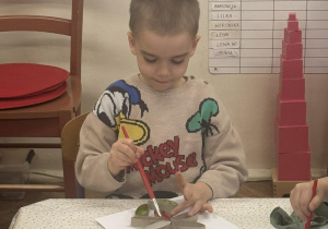 Na zdjęciu widać chłopca malującego farbami swoją pracę.