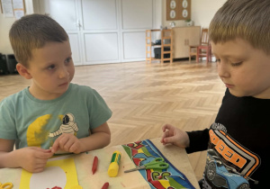 Zdjęcie przedstawia dzieci podczas wykonywania pisanki.