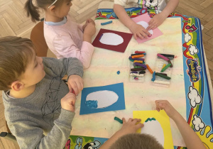 Zdjęcie przedstawia dzieci podczas wykonywania pisanki.
