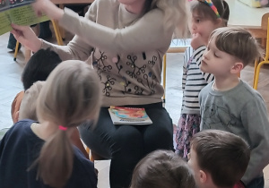 Pani czyta dzieciom książkę i pokazuje ilustrację.