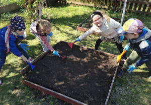 dzieci grabią posprzątaną rabatę