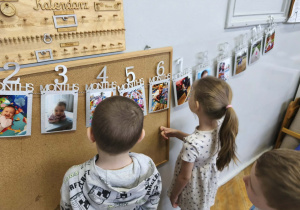 Na zdjęciu widzimy dzieci, które oglądają zdjęcia z różnych etapów życia Solenizantki.