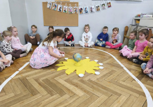 Na zdjęciu widzimy dziewczynkę, która rozkłada miseczki na słoneczku.