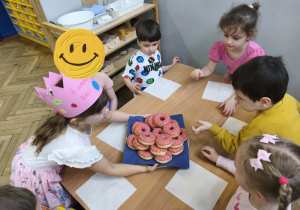 Na zdjęciu widzimy Solenizantkę częstującą dzieci donatami.