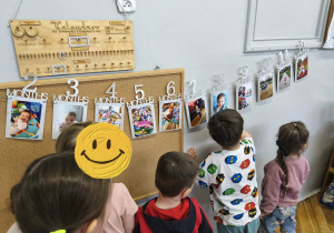 Na zdjęciu widzimy dzieci, które oglądają zdjęcia z różnych etapów życia Solenizantki.