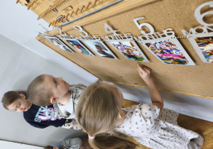 Na zdjęciu widzimy dzieci, które oglądają zdjęcia z różnych etapów życia Solenizantki.