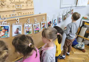 Na zdjęciu widzimy dzieci, które oglądają zdjęcia z różnych etapów życia Solenizantki.