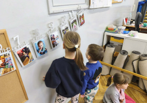 Na zdjęciu widzimy dzieci, które oglądają zdjęcia z różnych etapów życia Solenizantki.