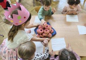 Na zdjęciu widzimy Solenizantkę częstującą dzieci donatami.