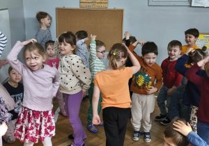 Na zdjęciu widzimy grupkę dzieci, które uczestniczą w zabawie ruchowej, której celem jest naśladowanie wymienionych zwierząt egzotycznych.