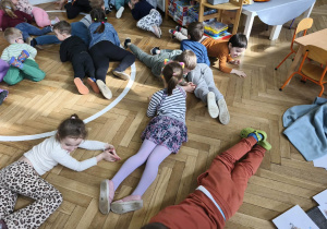 Na zdjęciu widzimy grupkę dzieci, które uczestniczą w zabawie ruchowej, której celem jest naśladowanie wymienionych zwierząt egzotycznych.