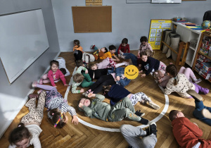 Na zdjęciu widzimy grupkę dzieci, które uczestniczą w zabawie ruchowej, której celem jest naśladowanie wymienionych zwierząt egzotycznych.