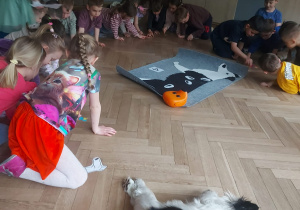 Dzieci układają na swoich obrazkach taka ilość kolorowych kropek ile na dużej macie wskazuje liczba. Kolorowe plamki symbolizują pchły