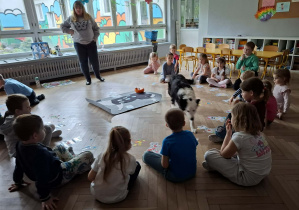 Dzieci witają się z psem i słuchają zasad zabawy