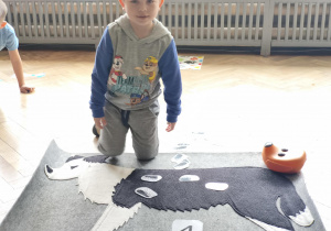 Dziecko ukłąda na macie psa- wskazana ilość pchełek jak wzór dla pozostałych dzieci