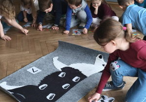 Dziecko ukłąda na macie psa- wskazana ilość pchełek jak wzór dla pozostałych dzieci