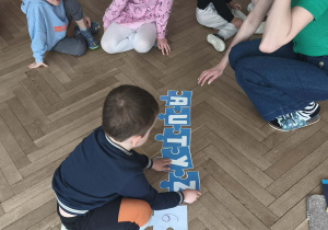 Dzieci układają puzzle - napis autyzm